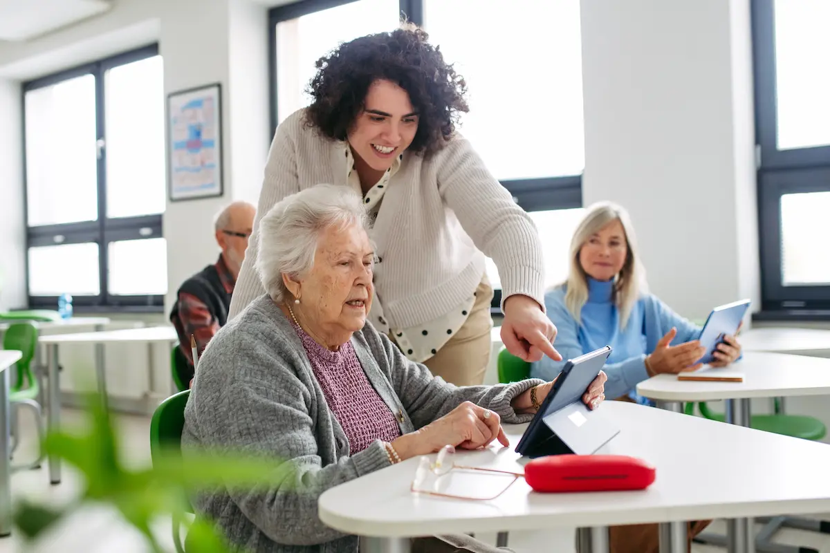 Seniorin lernt mit i-Restore Care Mitarbeiterin das Tablet zu nutzen — Digital-Sprechstunde in einer Senioreneinrichtung